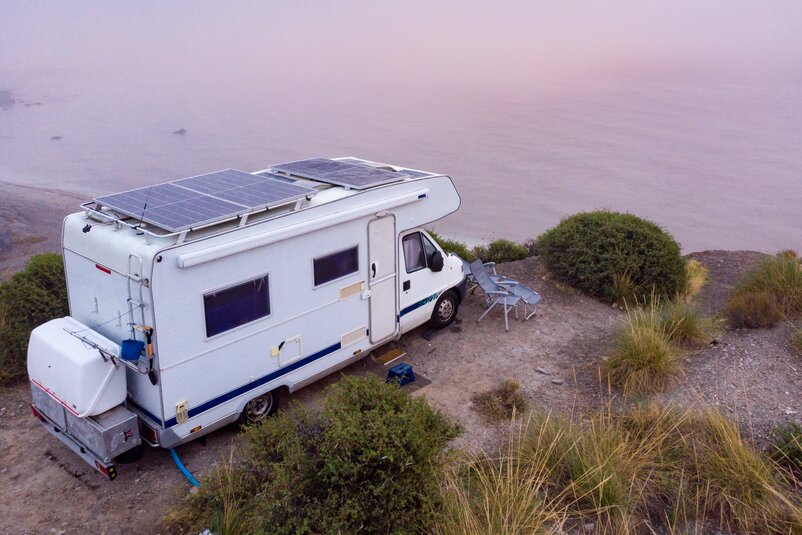 A camper van parked on a coastline overlooking the sea.
