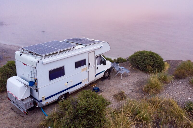 A camper van parked on a coastline overlooking the sea.