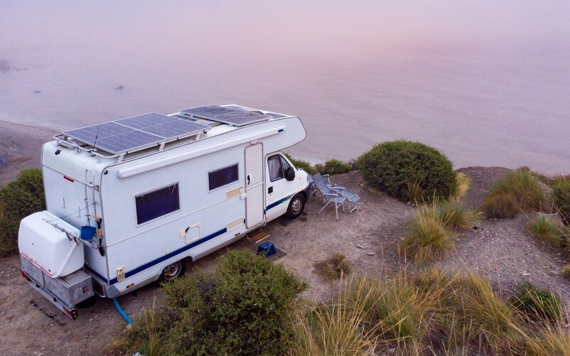 A camper van parked on a coastline overlooking the sea.