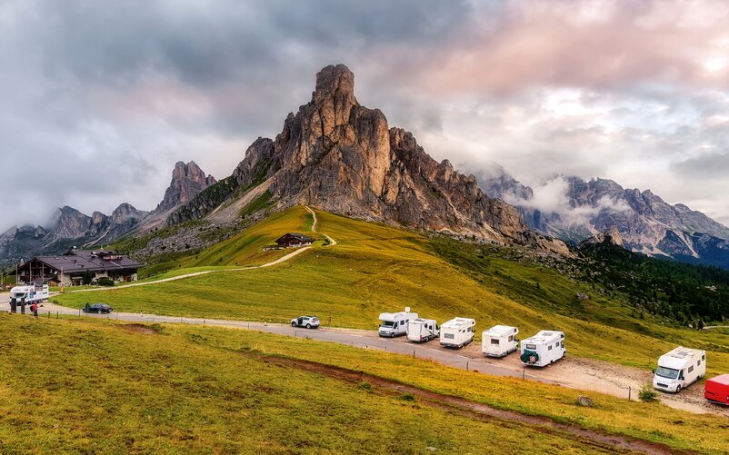 Several motorhomes are parked in an alpine region on a car park.