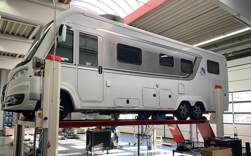 Ein weißes Wohnmobil auf einer Hebebühne in einer Werkstatt. | © AL-KO
