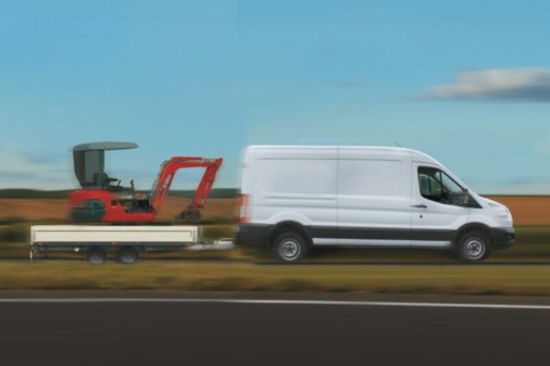 Ein Transporter mit einer hohen Anhängerlast zieht einen Anhänger mit Minibagger.